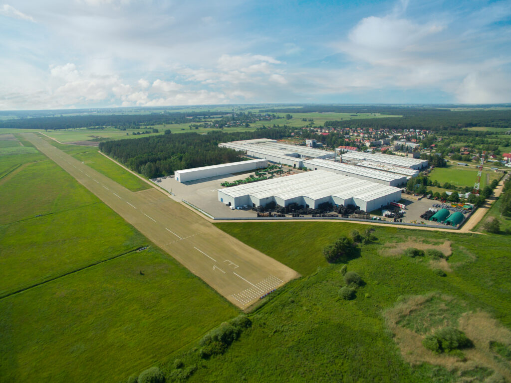 Zdjęcie lotnicze przedstawiające fabrykę maszyn rolniczych firmy Pronar. Przed fabryką pas startowy dla samolotów.
