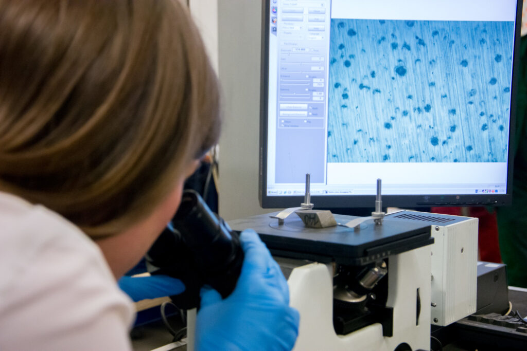 Kobieta w laboratorium patrząca przez mikroskop