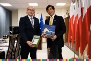 Artur Kosicki i ambasador Japonii pozują do zdjęcia z upominkami