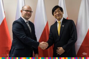 Artur Kosicki i ambasador Japonii podają sobie ręce pozując do zdjęcia