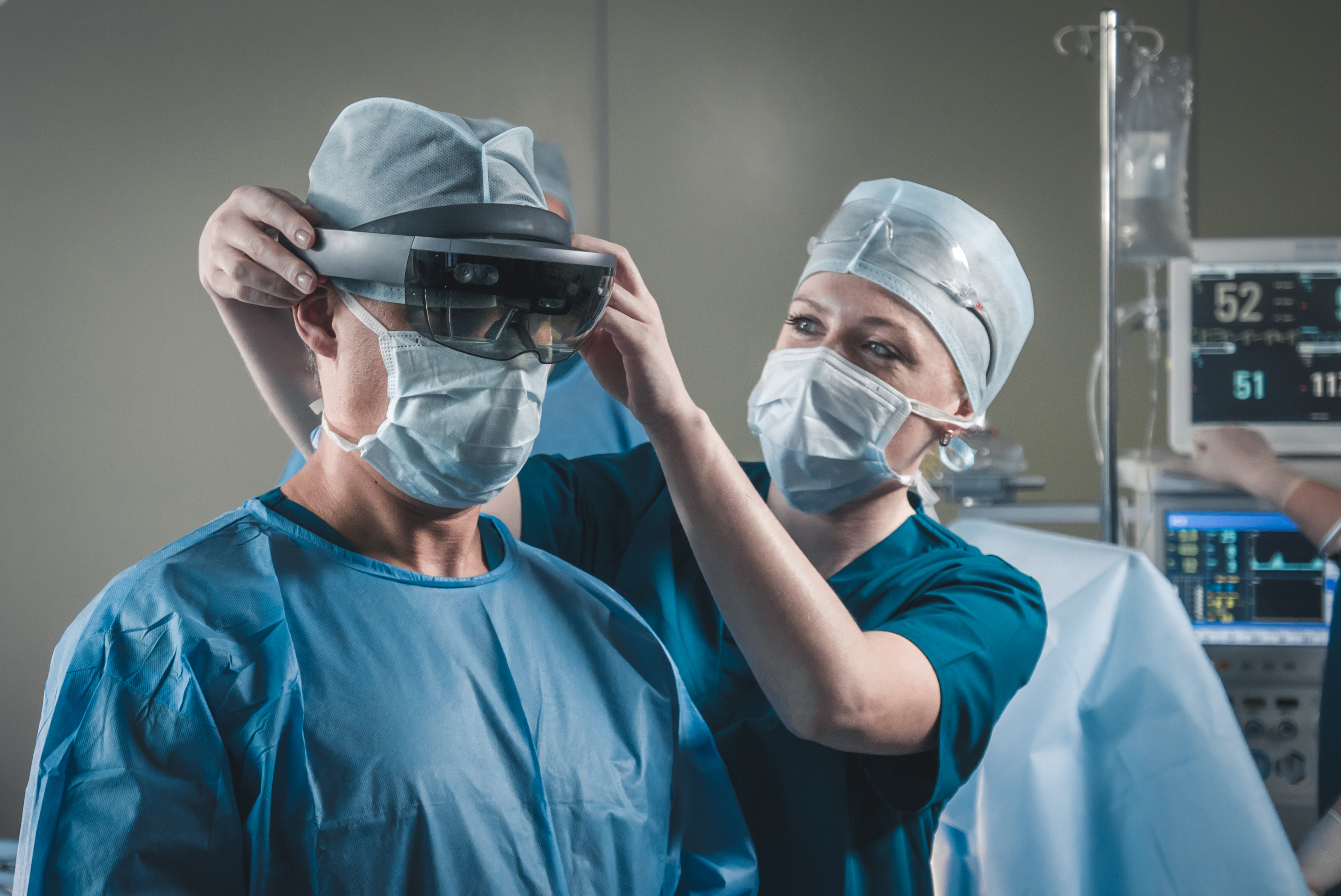 Pielęgniarka nakłada okulary chirurgowi na sali operacyjnej