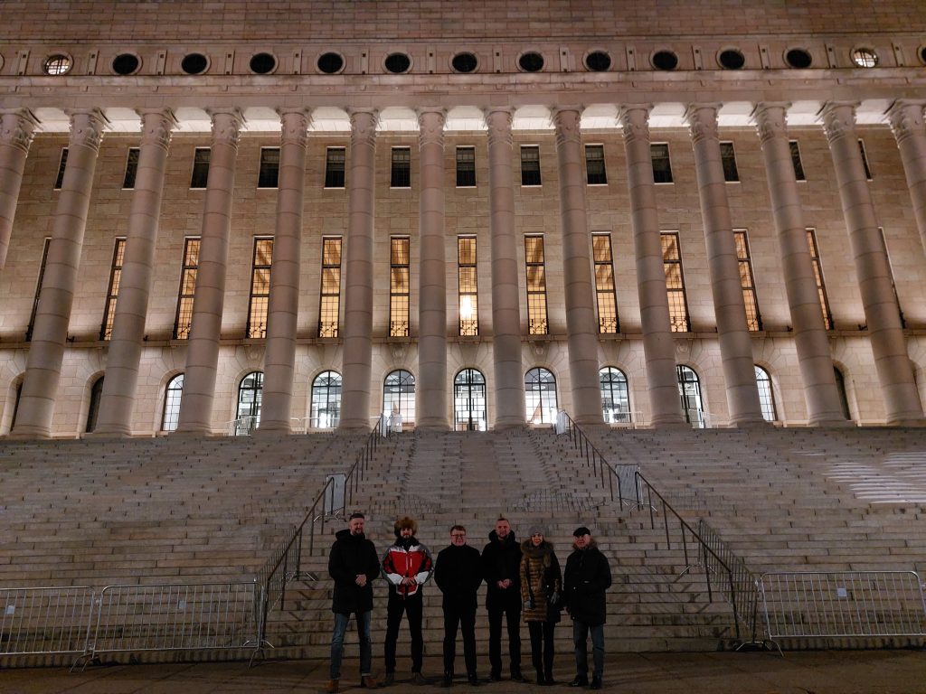 Uczestnicy misji gospodarczej Finlandii stoją na tle parlamentu w Helsinkach w Finlandii