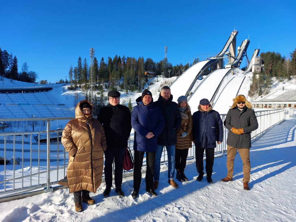 Uczestnicy misji gospodarczej stoją na tle skoczni narciarskiej w Lahti w Finslandii